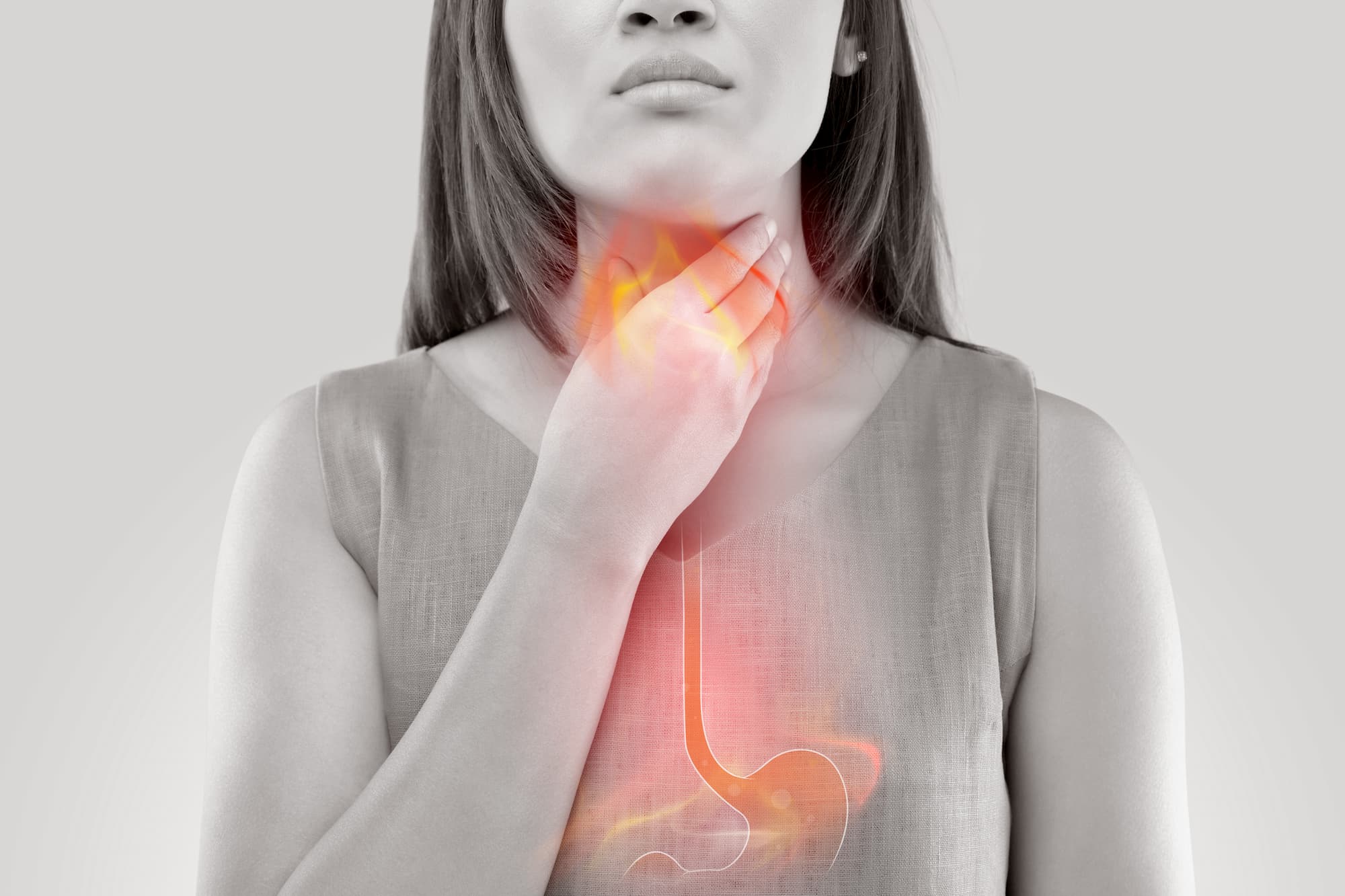 a woman holding her neck in discomfort because she is suffering from acid reflux