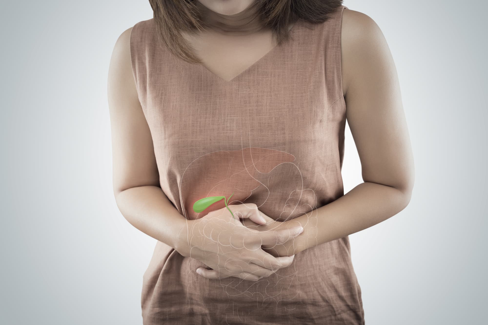 AdobeStock_301924589 a woman holding her stomach in pain whilst a diagram of the liver, gallbladder and bile passage is pasted over the top and the gallbladder is highlighted in green.