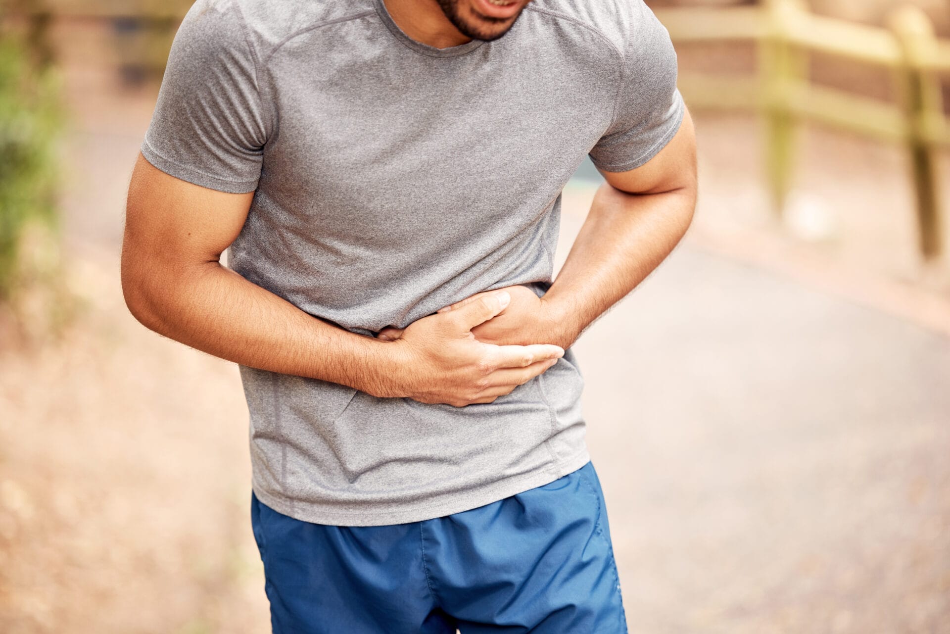 Fitness, stomach ache and man outdoor after running, workout or exercise. Sports, abdominal pain and male athlete in nature with injury, emergency or problem, sick or hernia after training mockup