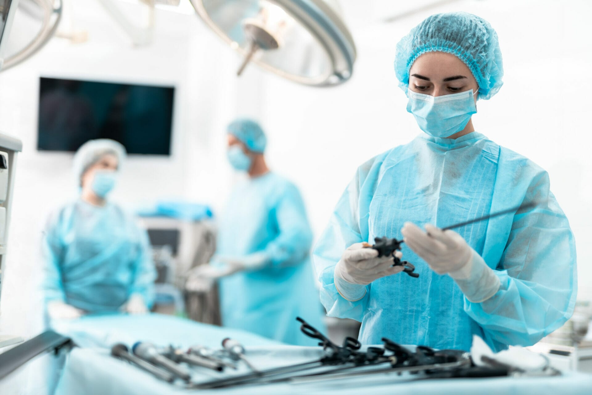 Young nurse in blue gown holding laparoscopic instrument